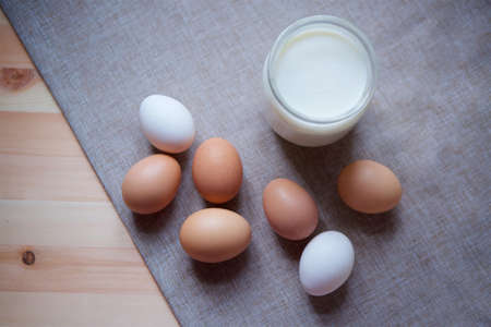 Rustic homemade chicken eggs of different varieties and a jar of fresh cow's milk.の写真素材