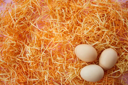 Three chicken eggs on a bright orange background. Concept of natural ecological products. The Christian holiday Easter.の写真素材