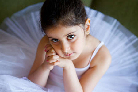 Little girl ballerina in white tutu sitting on floor in ballet class.の写真素材