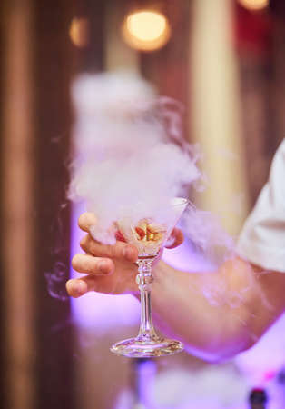 Alcoholic cocktail or champagne with smoke in the hands of the bartender.の写真素材