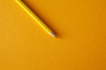 Yellow colored pencil lying on a bright yellow background, macro photography.の写真素材