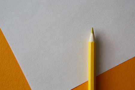 Yellow colored pencil lying on a bright yellow and white background, macro photography.の写真素材
