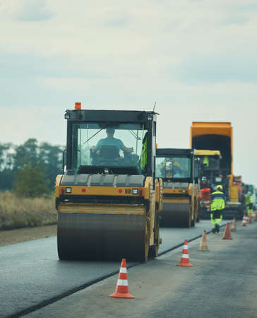 Asphalt pavers and industrial machines in the process of manufacturing pavement.