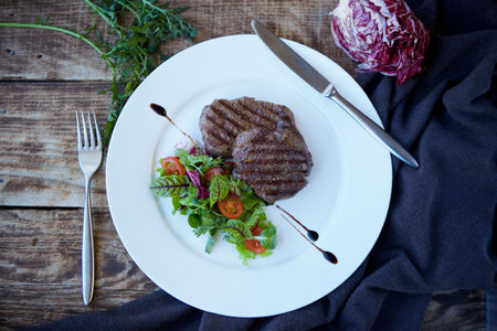 Pieces of fried meat lie on a white plate. Decorated with vegetables and herbs. The concept of...