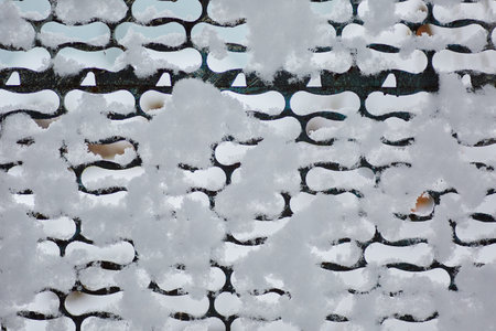 Old iron fence netting covered with snow in winter in the villageの写真素材