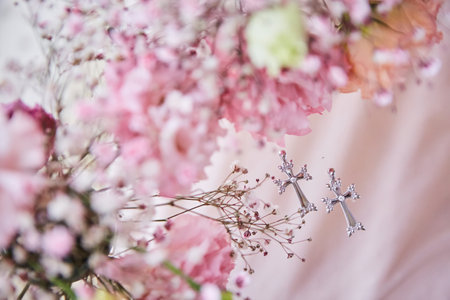 Two Christian crosses on a pink background surrounded by flowers. A symbol of faith. A holiday in honor of the christening of two children.の写真素材
