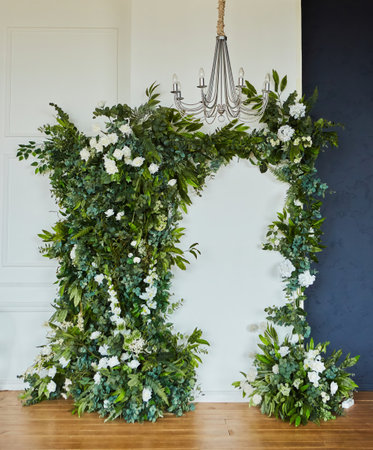 The wall of the room is decorated with vines and artificial flowers. A chandelier hangs from the ceiling. Interior decor for a holiday.の写真素材