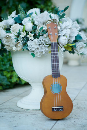 Beautiful acoustic guitar standing on the background of a large outdoor pot with flowers. Concept of music and concertの写真素材
