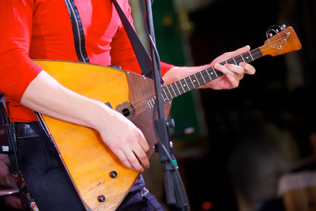 A balalaika stringed musical instrument in the hands of a male musician. The concept of culture and art.の写真素材