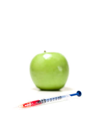 Green apple with syringe and red liquid, isolatedの写真素材