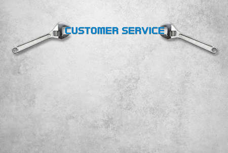 Wrench holds lettering customer service in front of a gray concrete wallの写真素材