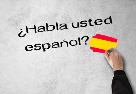 Business Man writes in Spanish, Spanish Do you speak on a wallの写真素材