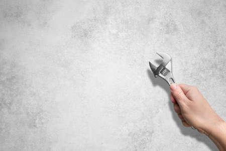 Man holding a wrench with a text concept on the concrete wall. But Now!の写真素材