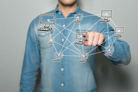 Young man pointing a virtual network on a touchscreen, with a gray background
