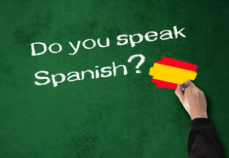 Business Man writes, do you speak Spanish on a wallの写真素材