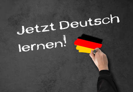 Man, teacher writes "Learning German now!" on a wallの写真素材