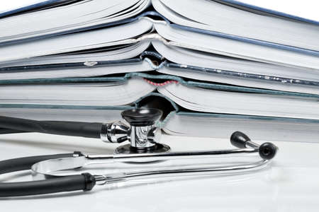Many pitched books are placed in a stack and a stethoscopeの写真素材