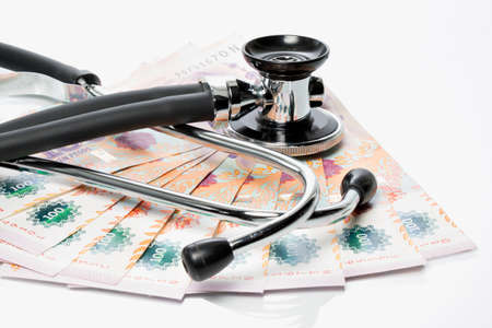 Peso bills with stethoscope and pills on a white tableの写真素材