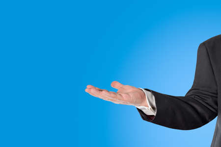 Businessman with an open hand in front of a blue backgroundの写真素材