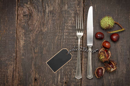 Cutlery and chestnuts lie on a rustic old wooden tableの写真素材