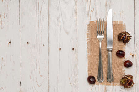 Cutlery and chestnuts lie on a rustic old wooden tableの写真素材