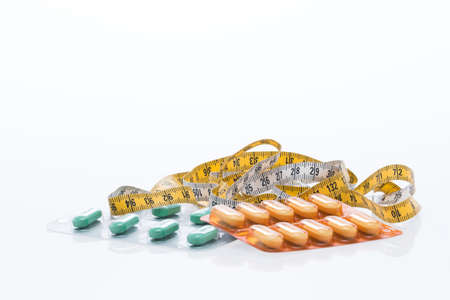 Tape measure and pills on a white tableの写真素材