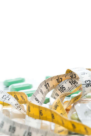 Tape measure and pills on a white tableの写真素材