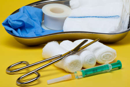 Plasters and bandages with Scissors and syringe on a yellow backgroundの写真素材