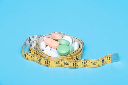 Tape measure and pills on a blue backgroundの写真素材