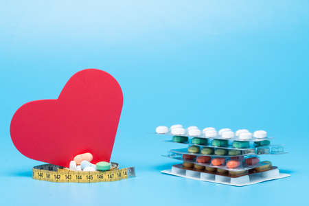 Tape measure, pills and a red heart on a blue backgroundの写真素材