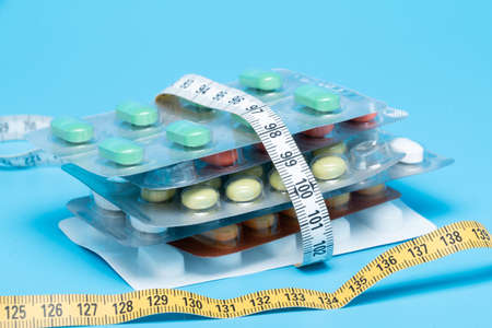 Tape measure and pills on a white tableの写真素材