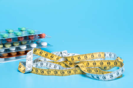 Tape measure and pills on a white table