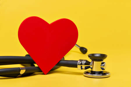 Stethoscope with red heart on yellow background