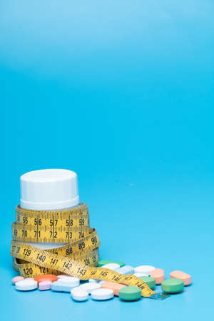Tape measure and pills on a blue backgroundの写真素材