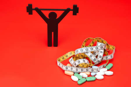 weightlifting pictogram with pills and tape measure, red backgroundの写真素材