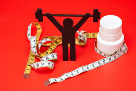 weight lifting pictogram with pills and tape measure, red backgroundの写真素材