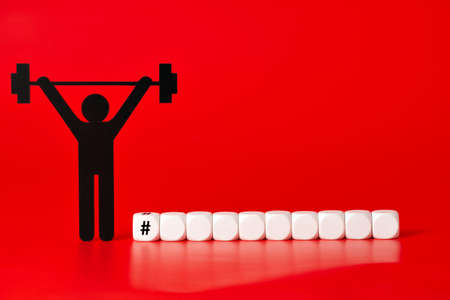 Black weight lifter pictogram with white unlabeled cubes, on red backgroundの写真素材