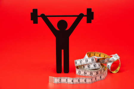 weightlifting pictogram with pills and tape measure, red backgroundの写真素材