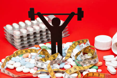 weightlifting pictogram with pills and tape measure, red backgroundの写真素材