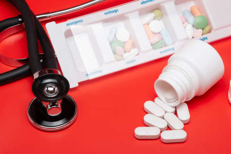 Blister of tablets isolated, with stethoscope, on a red backgroundの写真素材