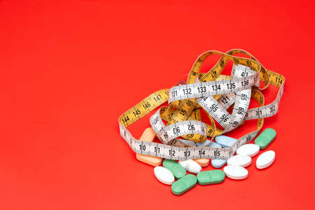 Tape measure and pills on a red backgroundの写真素材