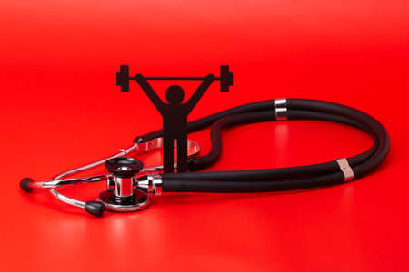 Weight lifting pictogram, Stethoscope, close-up isolated with red backgroundの写真素材