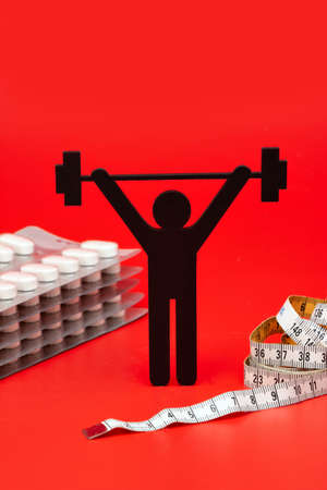weightlifting pictogram with pills and tape measure, red backgroundの写真素材
