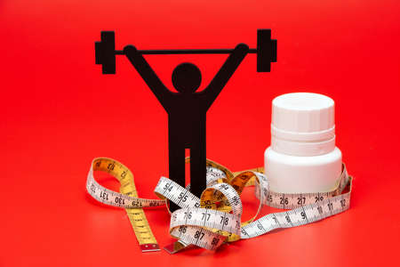 weight lifting pictogram with pills and tape measure, red backgroundの写真素材