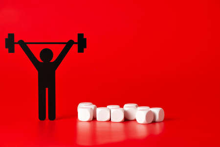 Black weight lifter pictogram with white unlabeled cubes, on red backgroundの写真素材