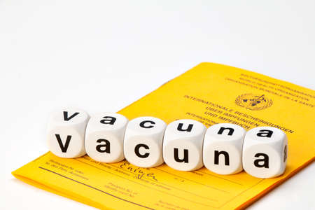 Syringe with vaccine and International Vaccination Passport. Vaccination written with dice. (Vacuna...