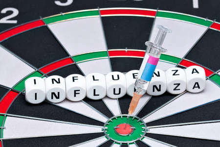 Syringe with flu vaccine is in dartboard