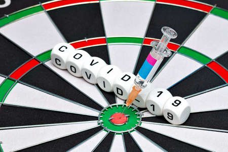 Syringe with Covid-19 vaccine is in the dartboard
