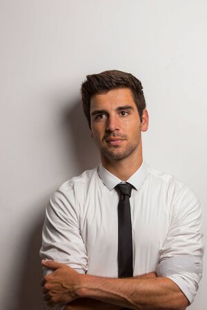 Young man with shirt and tie crossed his arms lost in thoughtsの写真素材