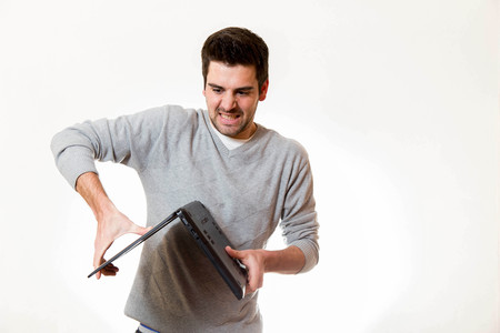 A young tries to break a laptop the other way aroundの写真素材